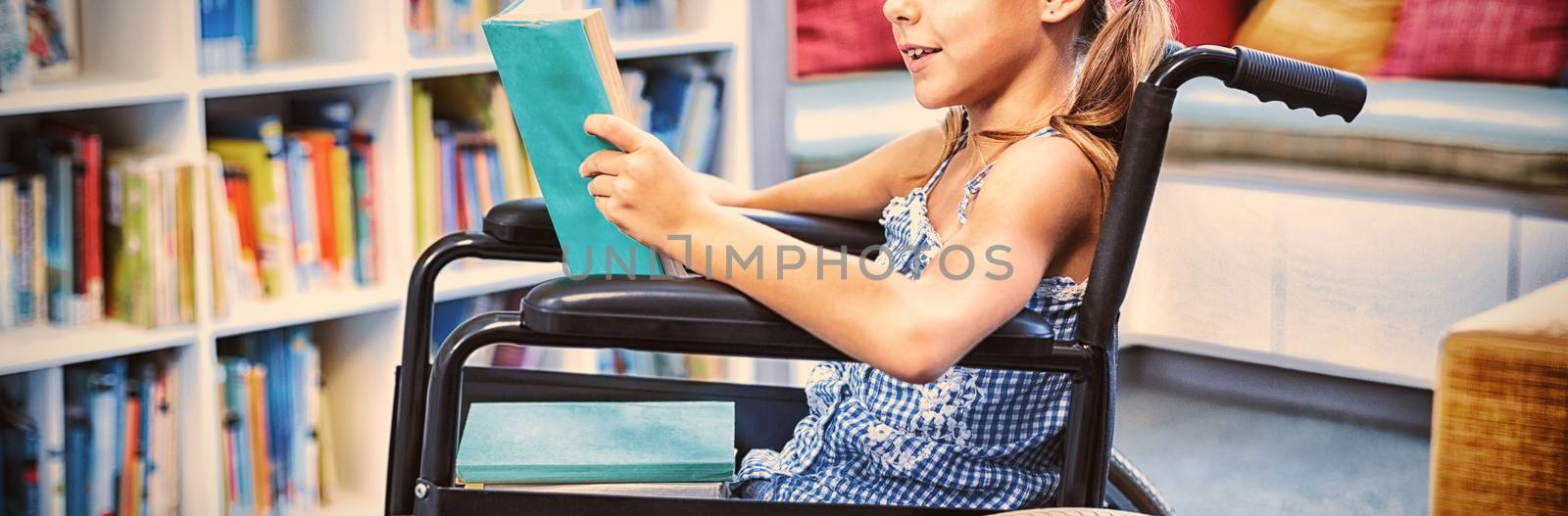 Disabled girl reading book in library by Wavebreakmedia