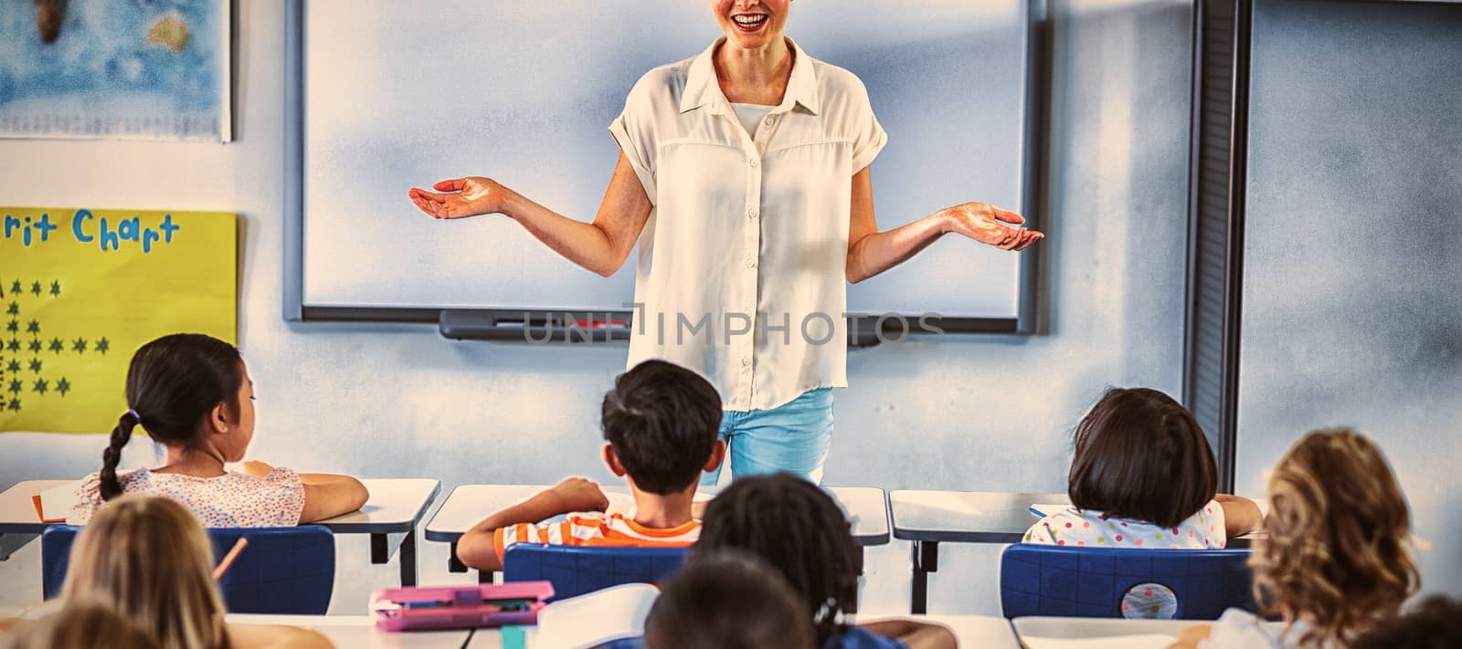 Portrait of smiling female teacher with arms outstretched in classroom