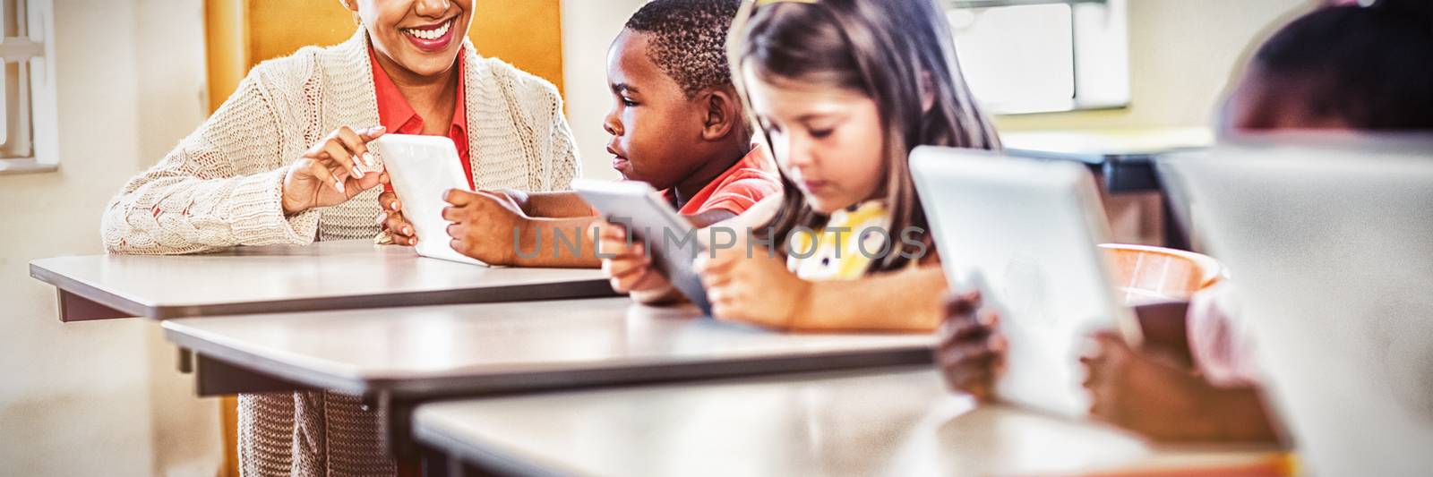 Teacher giving lesson to her students with technology at school