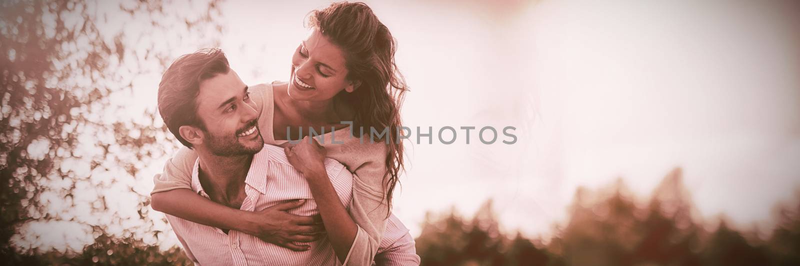 Young man piggybacking woman at farm during sunny day by Wavebreakmedia