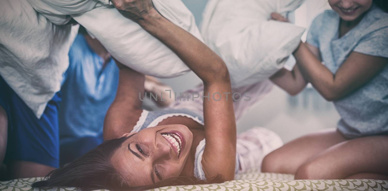 Family having pillow fight in bedroom by Wavebreakmedia
