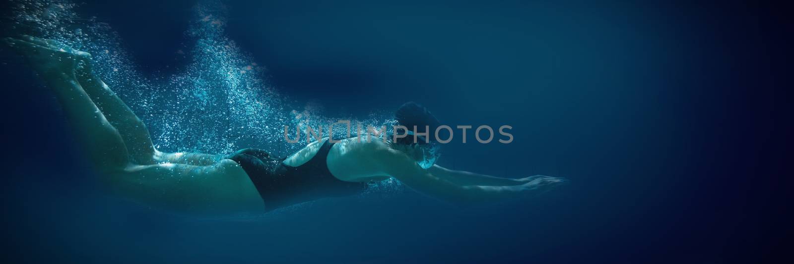 Athletic swimmer training on her own in the swimming pool at the leisure centre