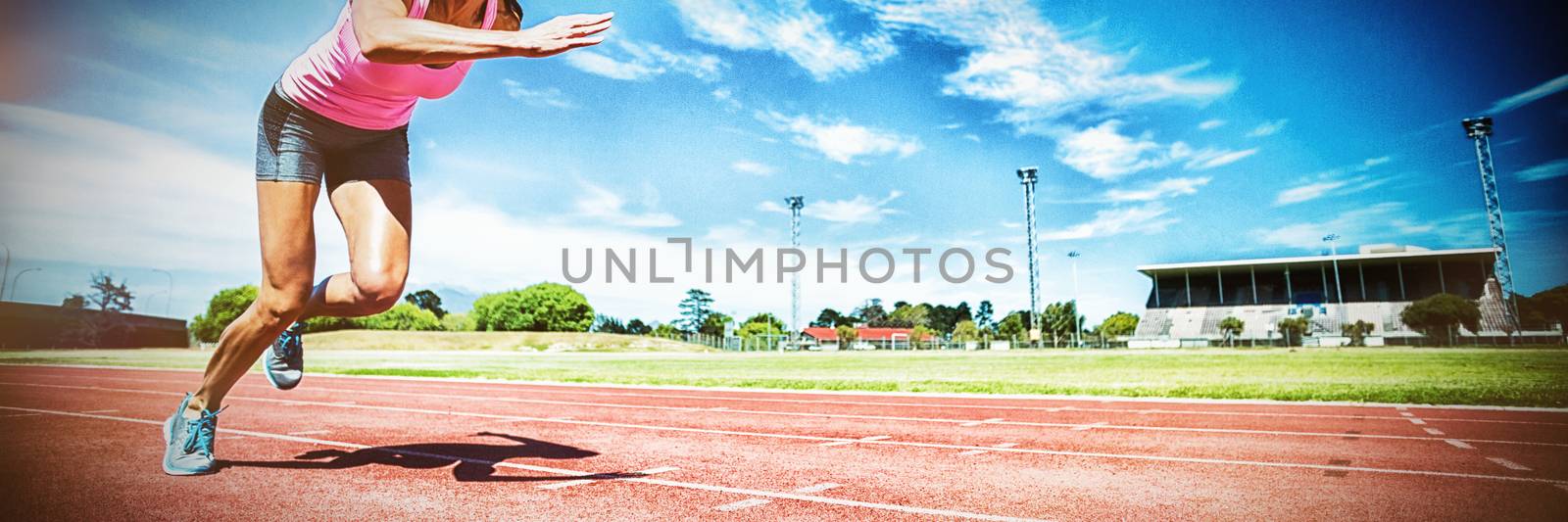 Female athlete running on running track on sunny day