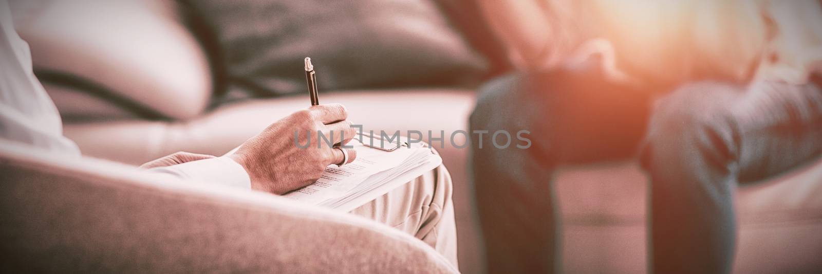 Therapist making notes of patient on sofa at home