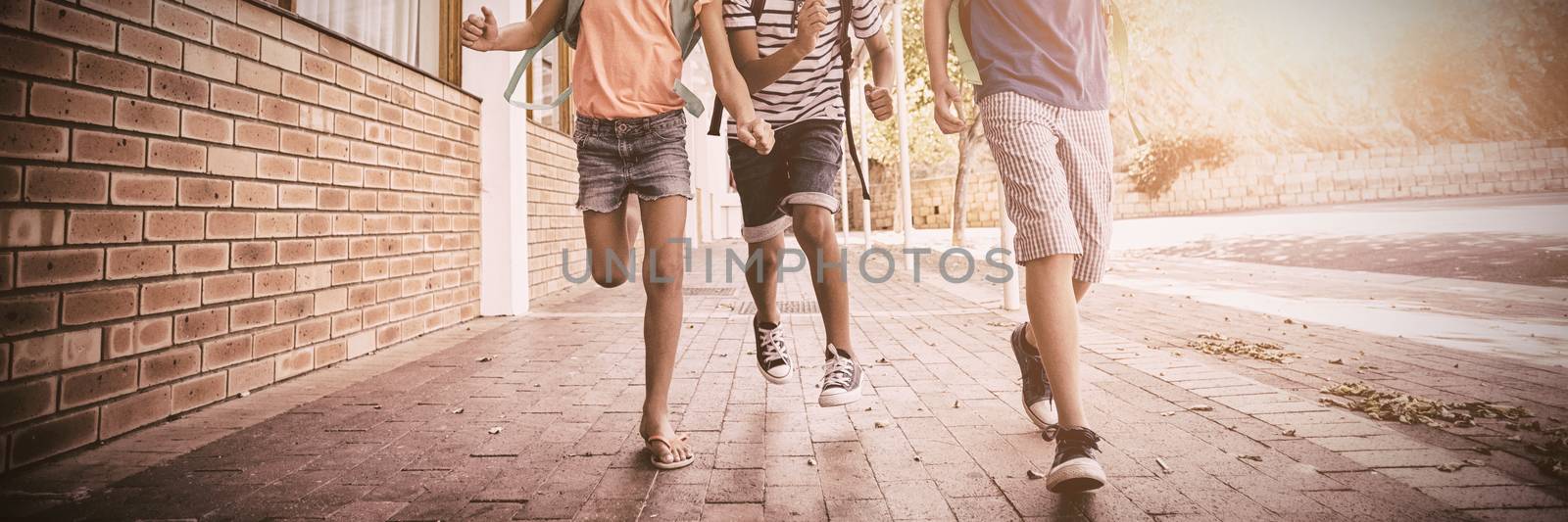 Happy school kids running in corridor at school