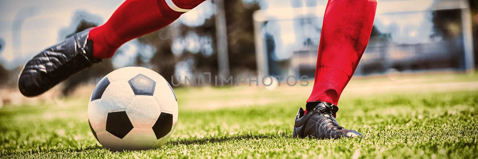 Low section of player practicing soccer on playing field