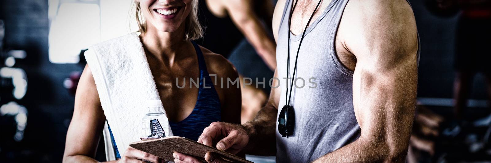 Portrait of smiling fitness instructor with woman standing in gym