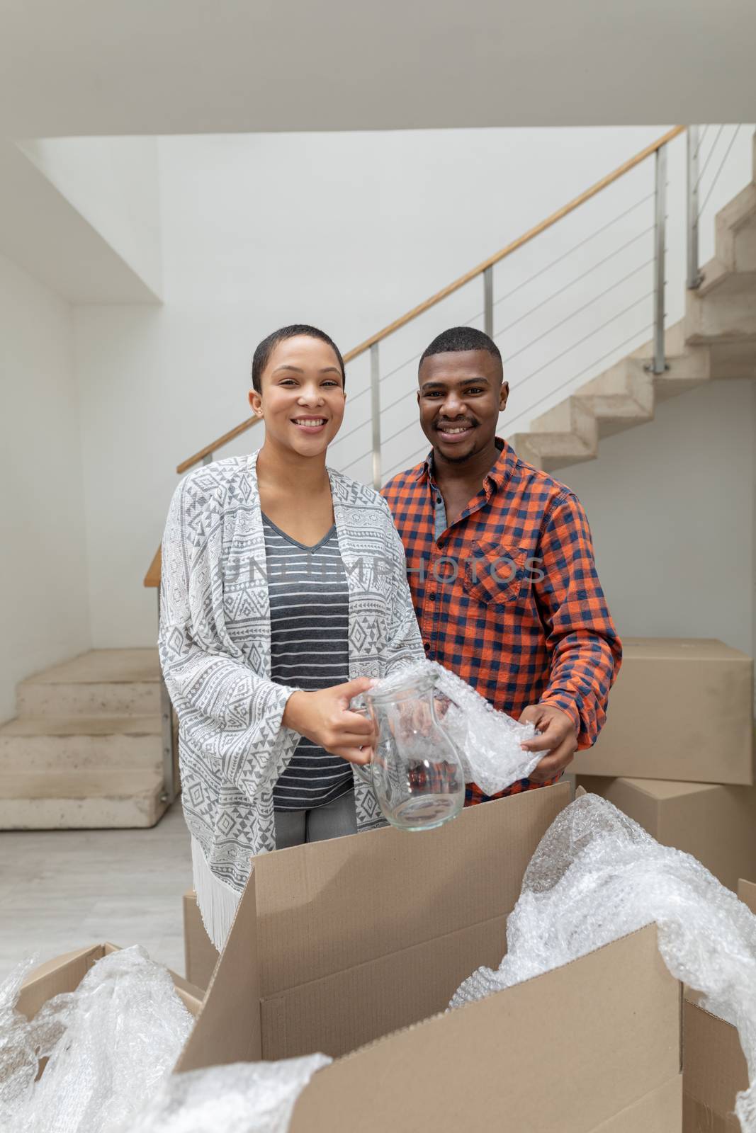 Front view of happy African american couple unpacking cardboard boxes in living room at home