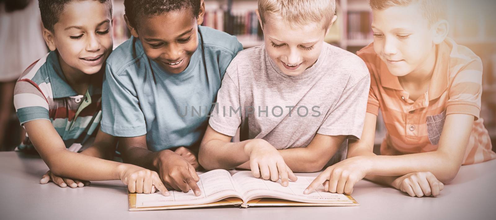 School kids reading book together in library at elementary school 