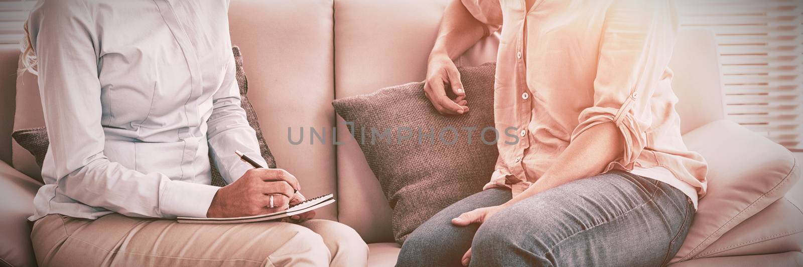 Smiling woman talking to therapist on sofa at home