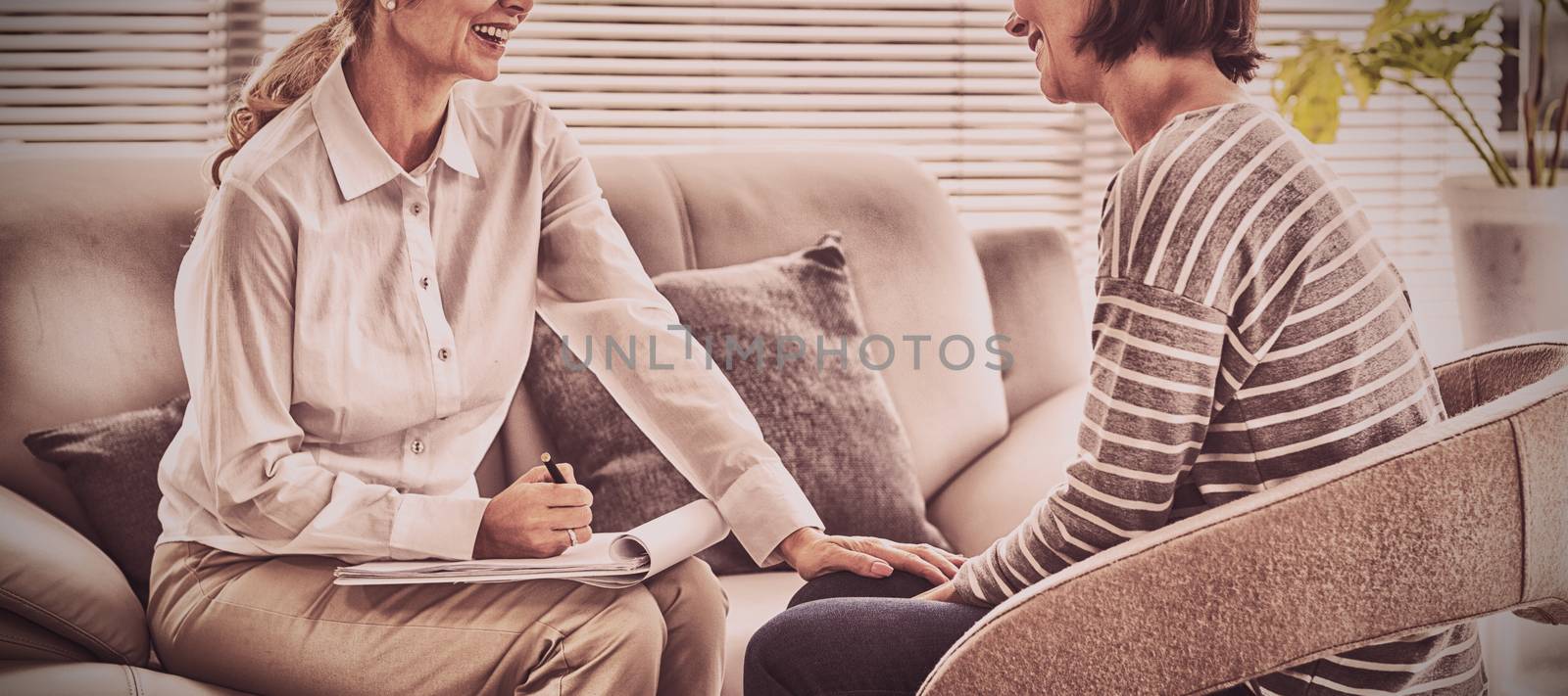 Happy therapist with patient on sofa at home