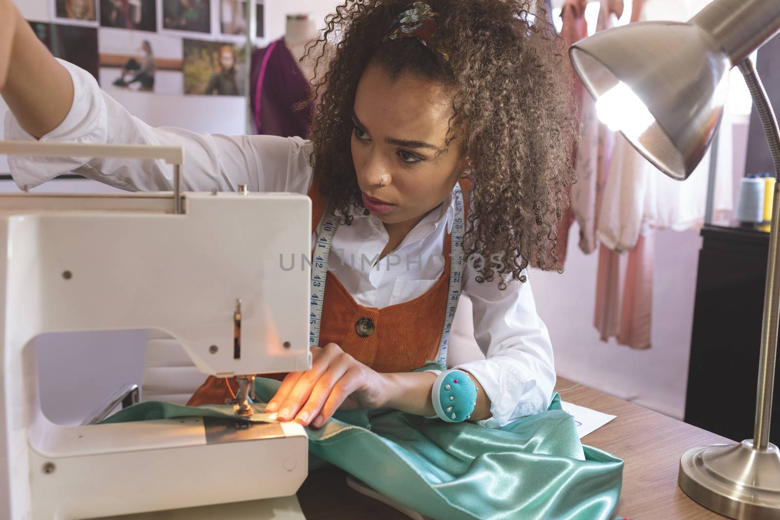 Front view of female fashion designer working with sewing machine