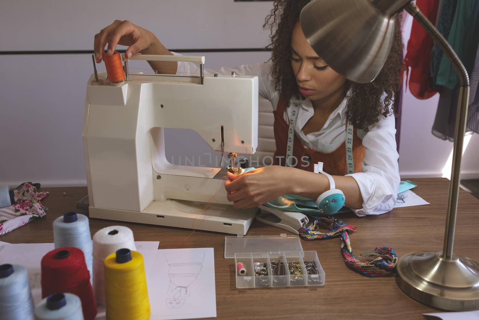 Front view of female fashion designer working with sewing machine