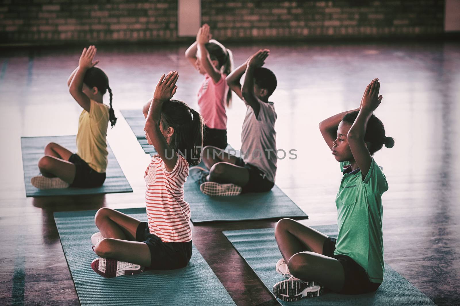 School kids meditating during yoga class by Wavebreakmedia