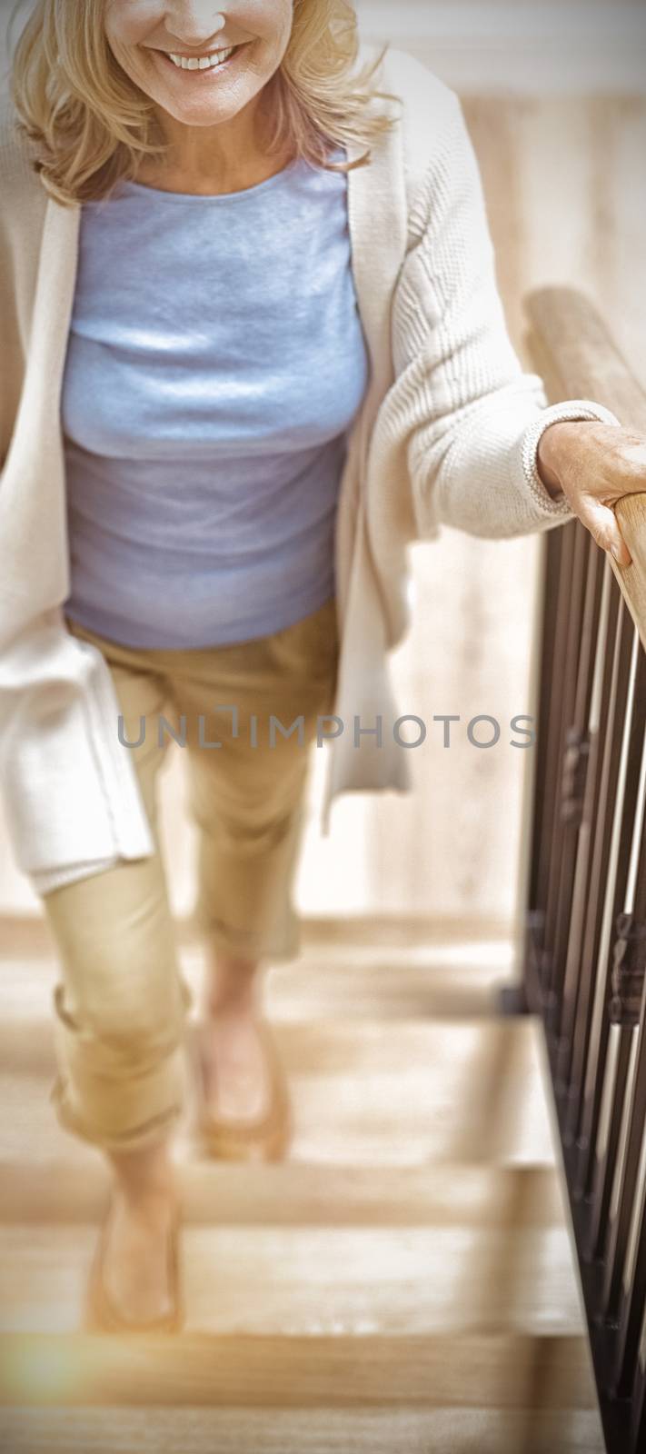 Portrait of smiling senior woman climbing upstairs at home