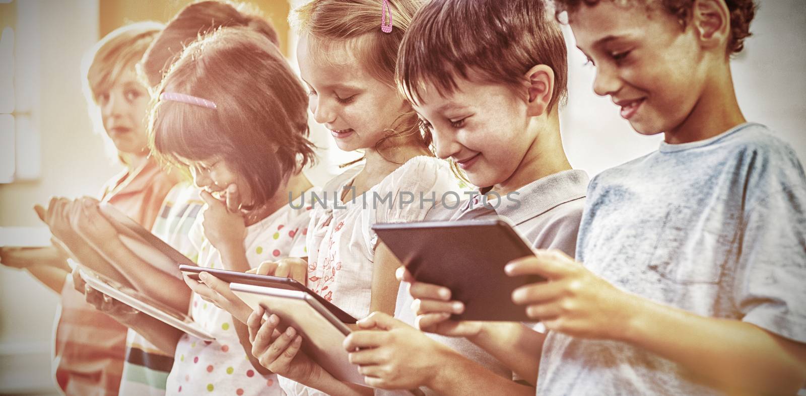 Smiling children using digital tablets in classroom