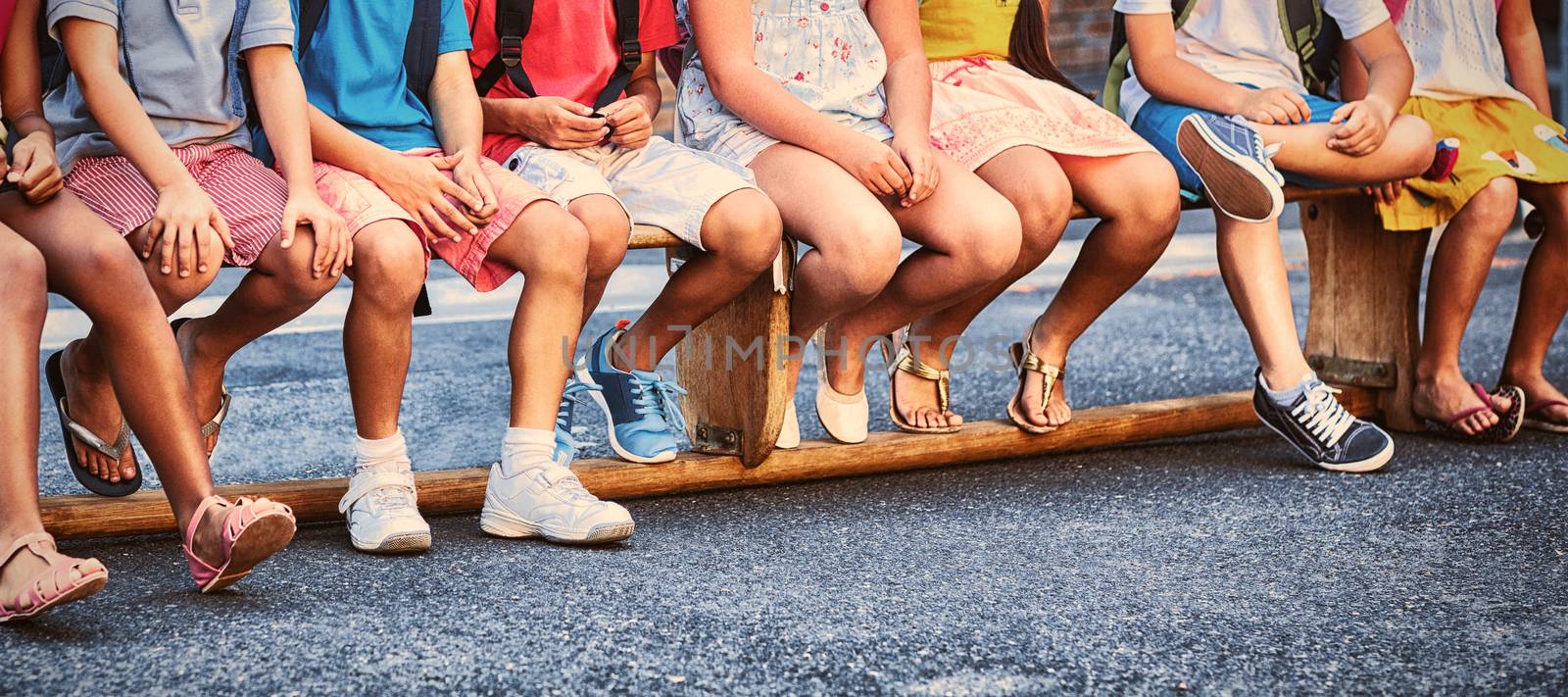 Portrait of smiling schoolchildren on seat outside school