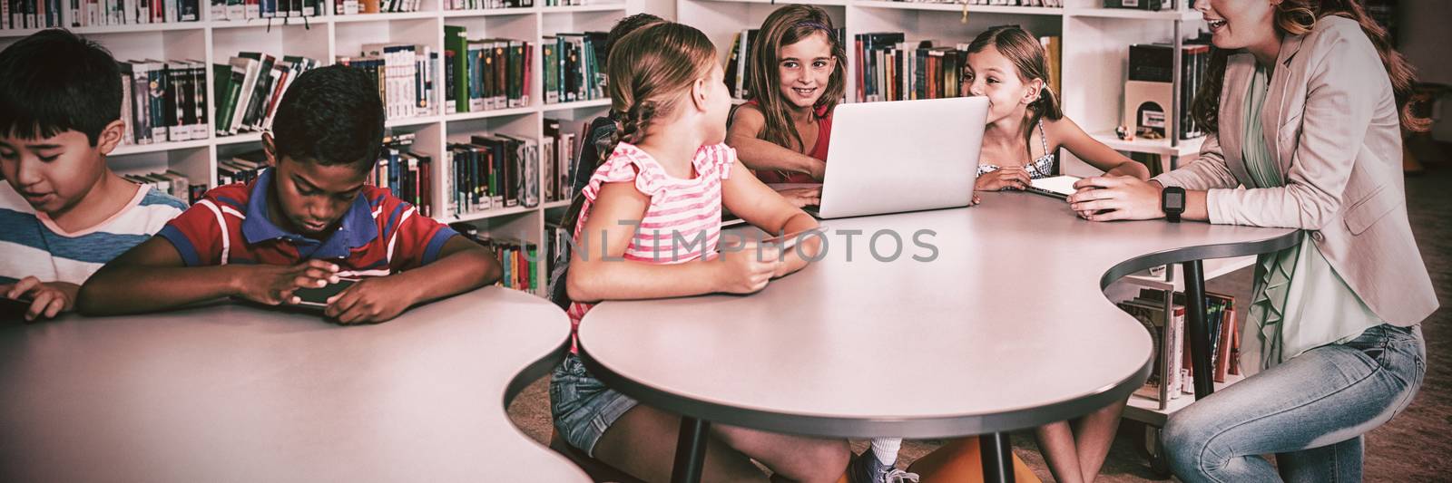 Teacher using technology with pupils in library