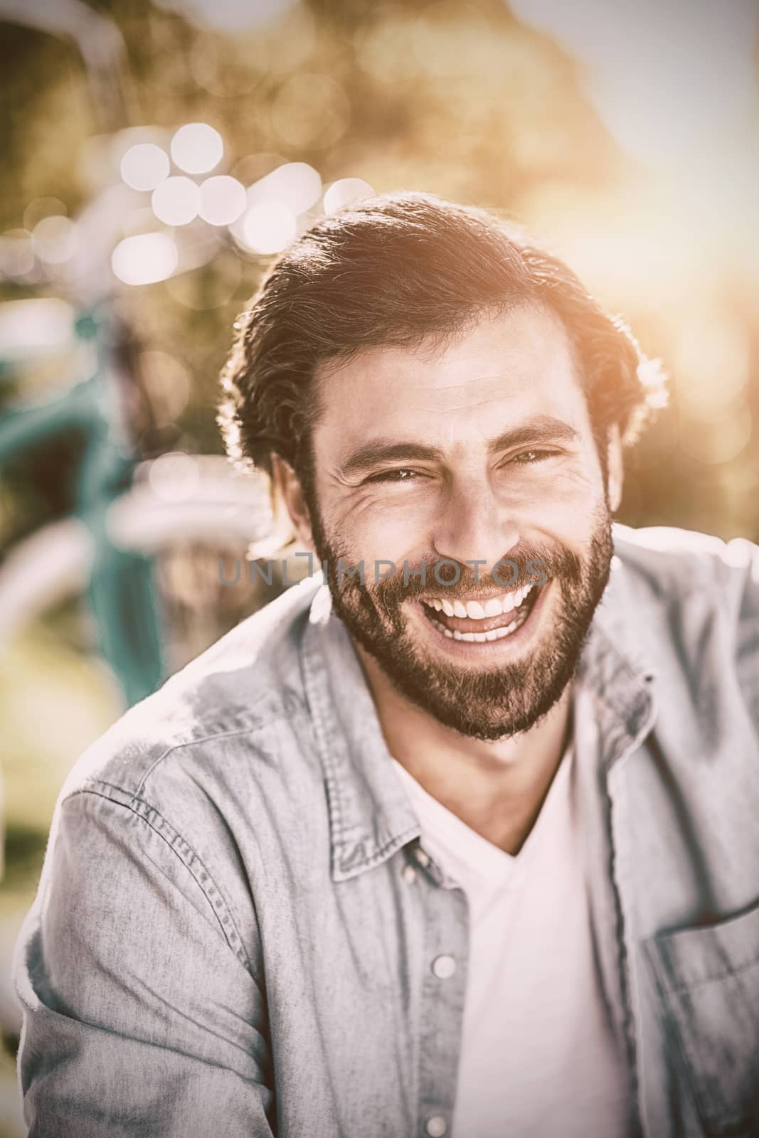 Portrait of handsome man smiling at camera in park on sunny day, Close-up