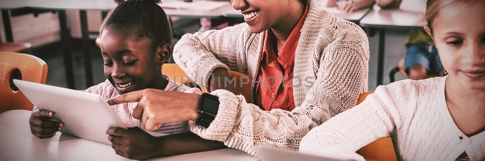 Teacher helping student with tablet computer by Wavebreakmedia