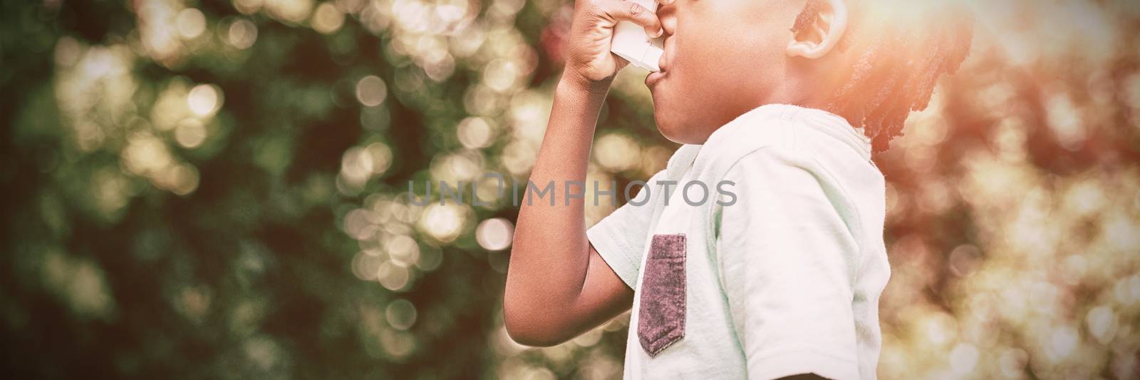 Boy using an asthma inhaler in the park