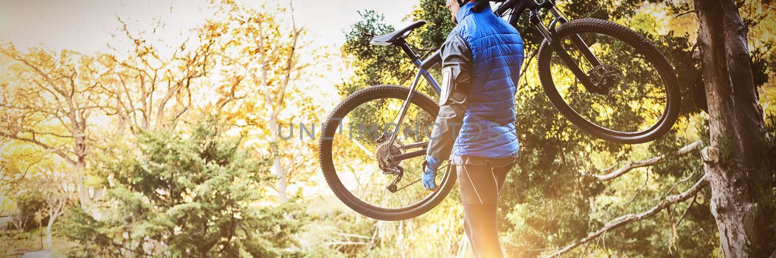 Male mountain biker carrying bicycle looking at nature in the forest