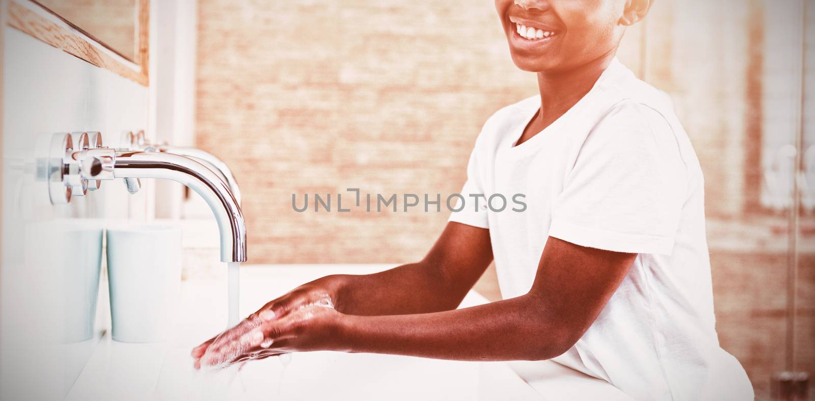 Portrait of smiling boy washing hands in sink by Wavebreakmedia