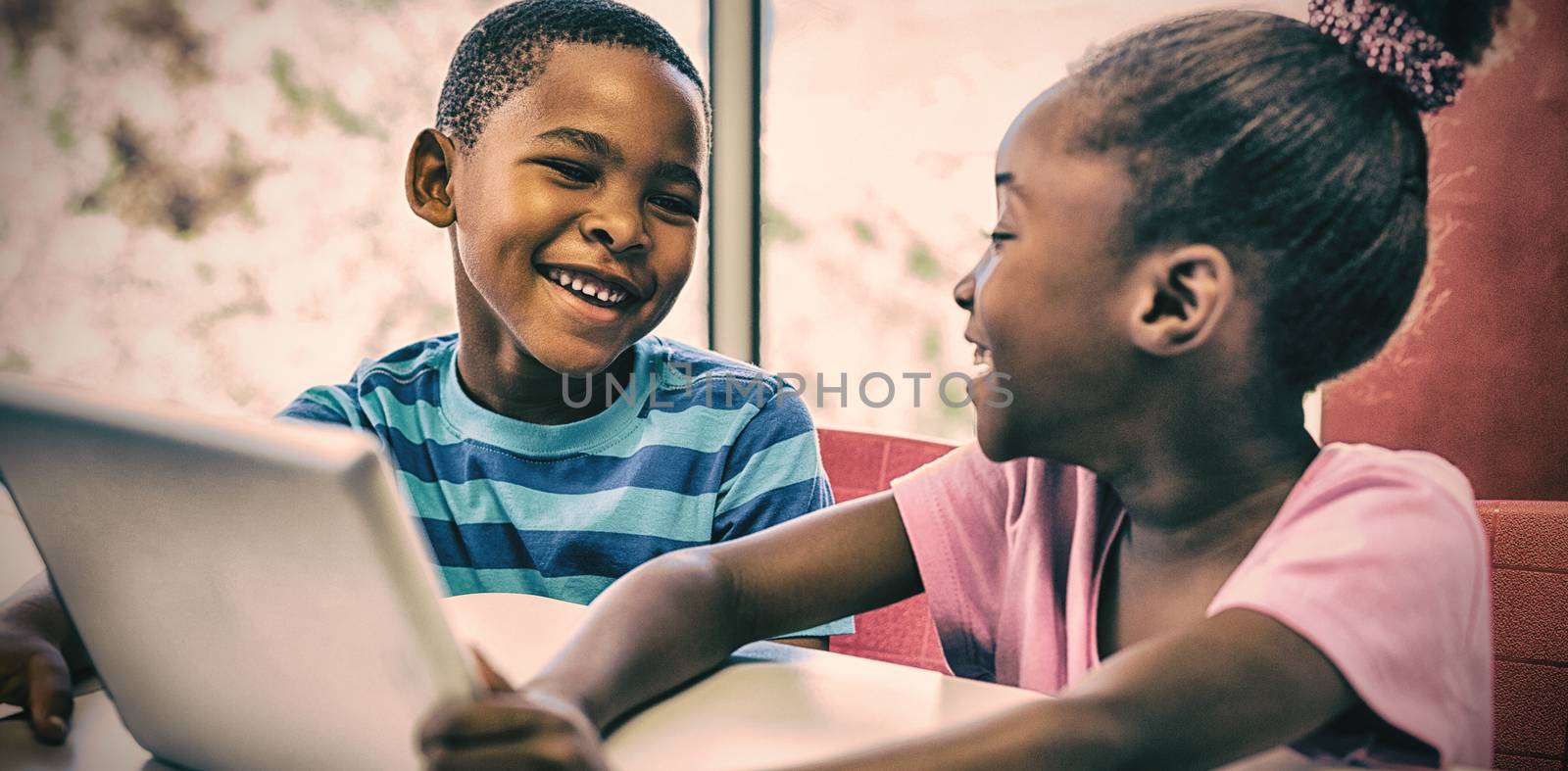 Smiling children using digital tablet in classroom at school