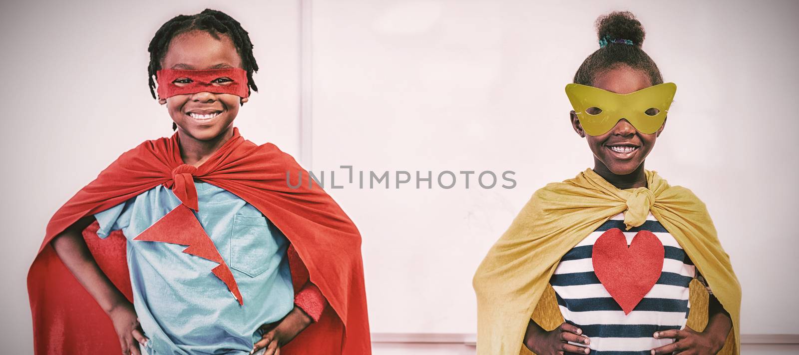 Boy and girl in eye mask and cape standing over white background