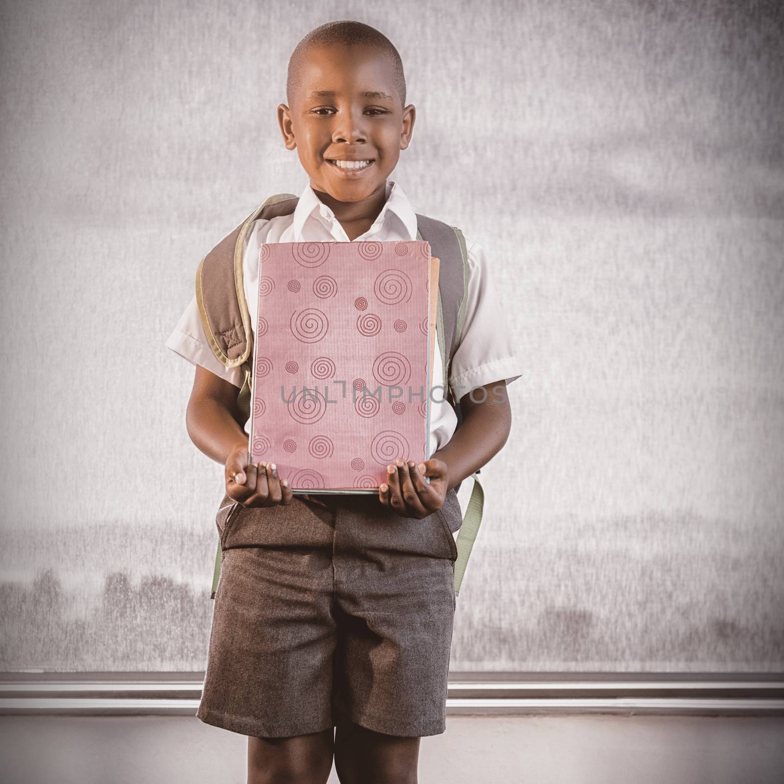 Happy schoolkid holding books and standing in classroom by Wavebreakmedia