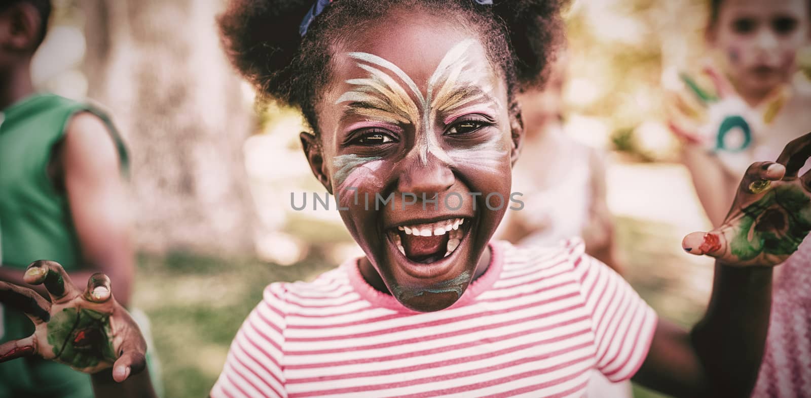 Portrait of a girl with make-up showing her painted hands in a park