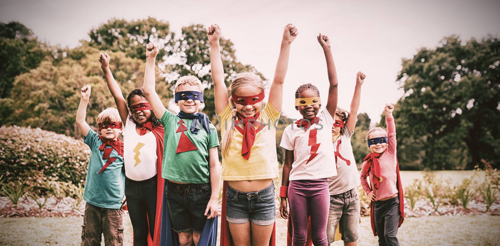 Children wearing superhero costume standing in the park