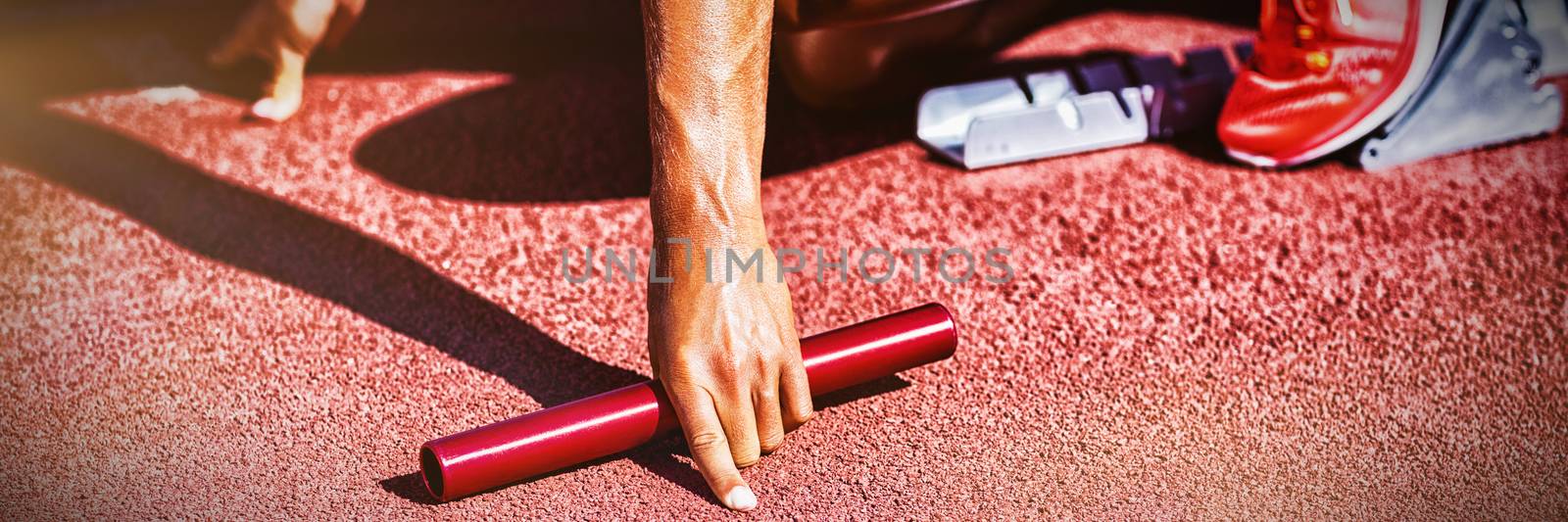 Female athlete ready to start relay race on running track