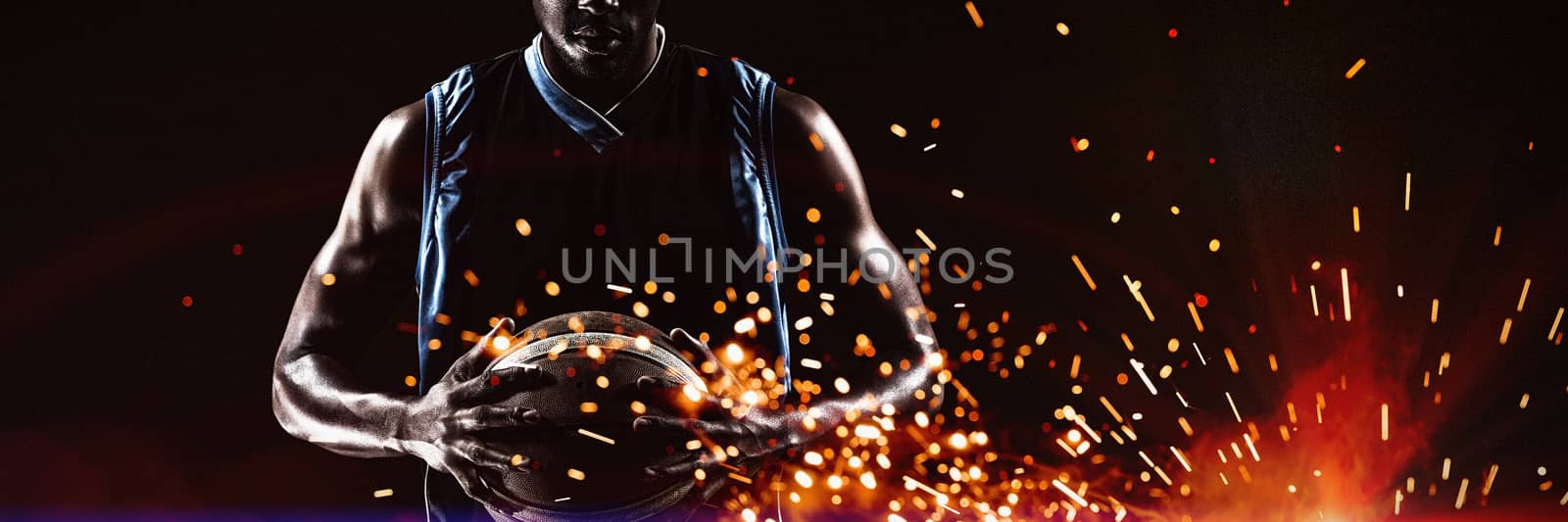 Sports player holding ball while standing against black background