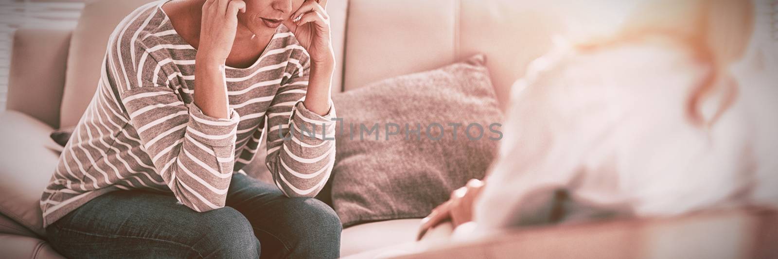 Sad woman sitting with therapist on sofa at home