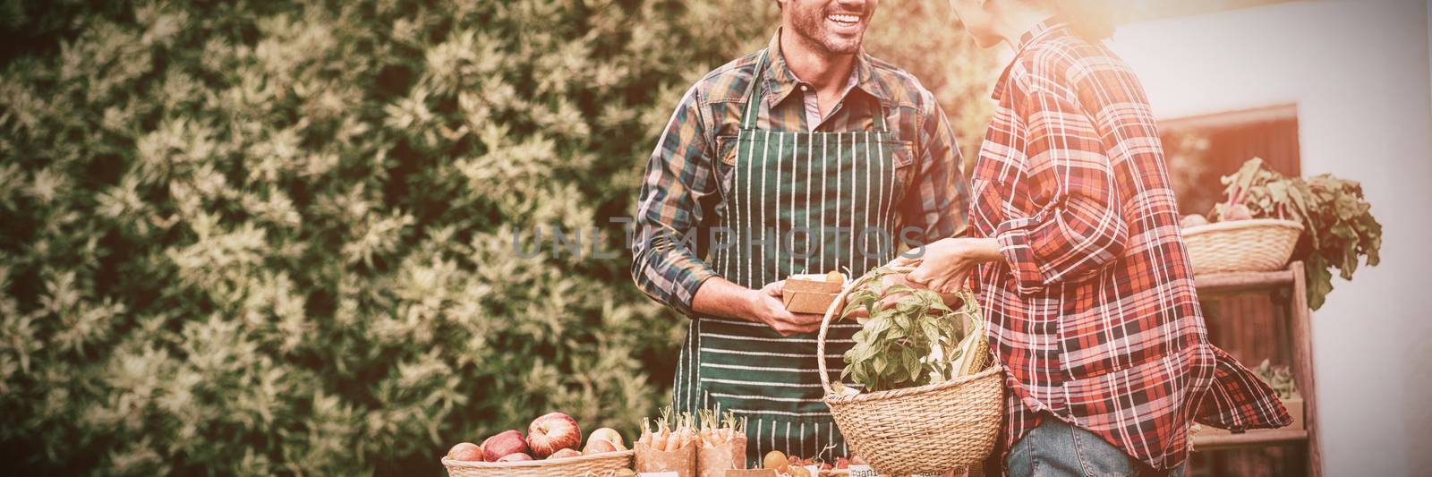 Woman buying organic vegetables from man by Wavebreakmedia