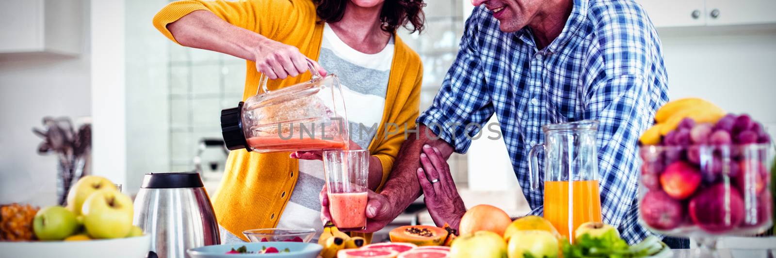 Happy couple preparing smoothie in kitchen by Wavebreakmedia