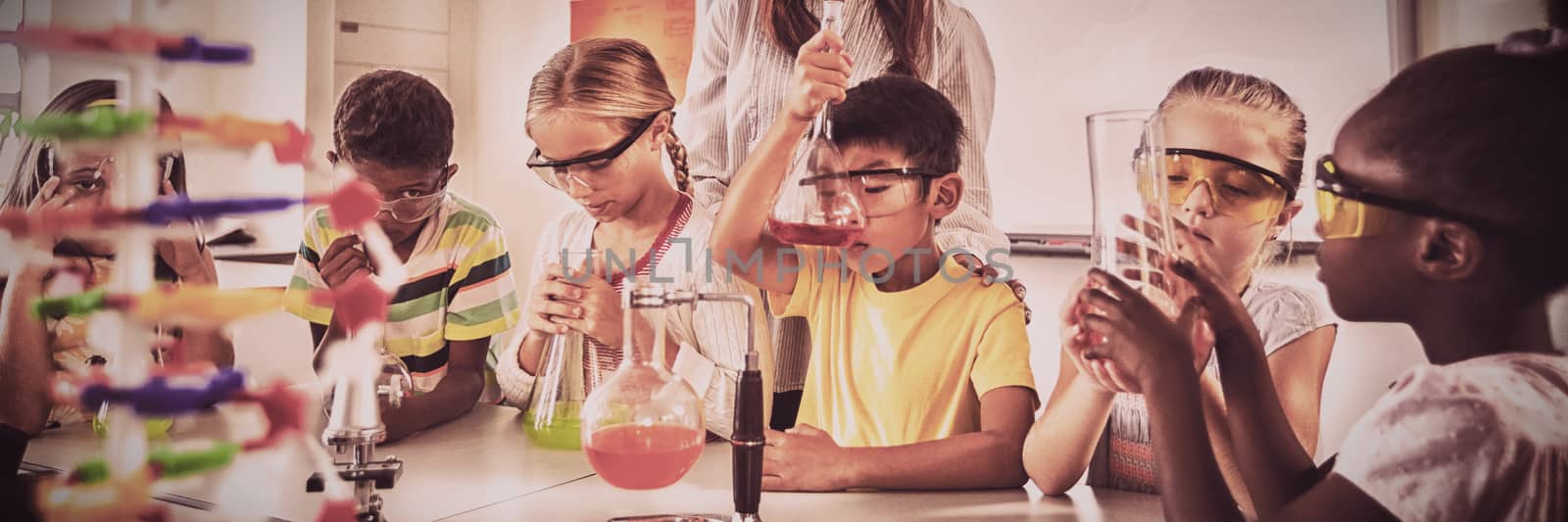 A teacher posing with pupils doing science project in classroom