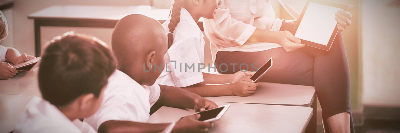 Teacher teaching kids on digital tablet by Wavebreakmedia