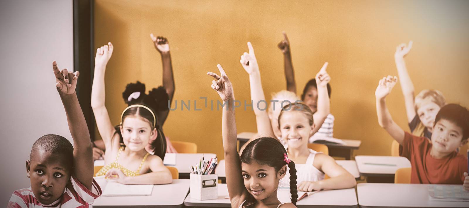 Students raising hands in classroom by Wavebreakmedia