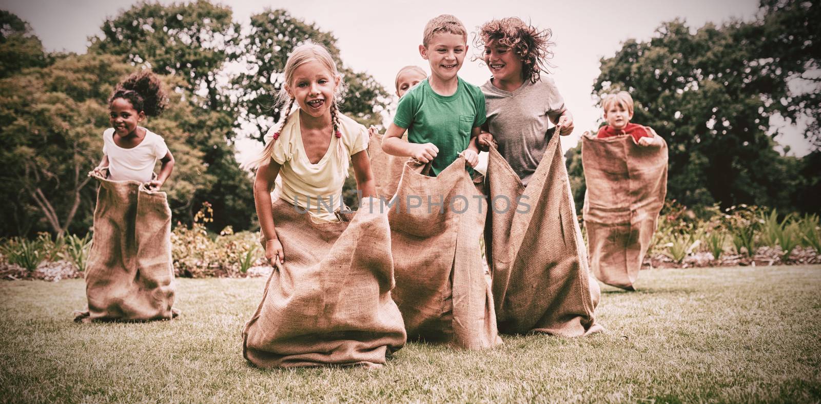 Children having a sack race in park on a sunny day