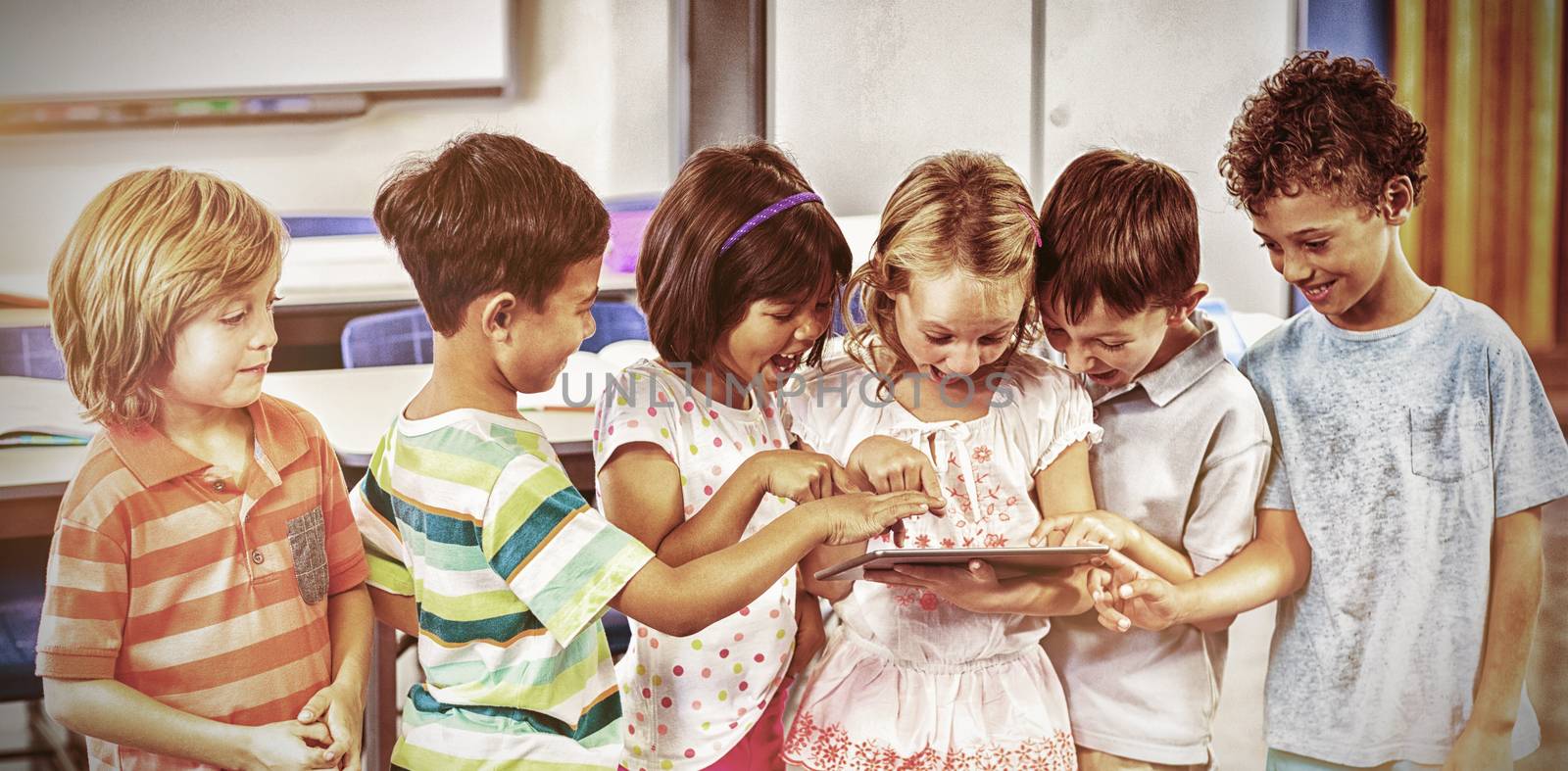 Happy schoolchildren using digital tablet in classroom