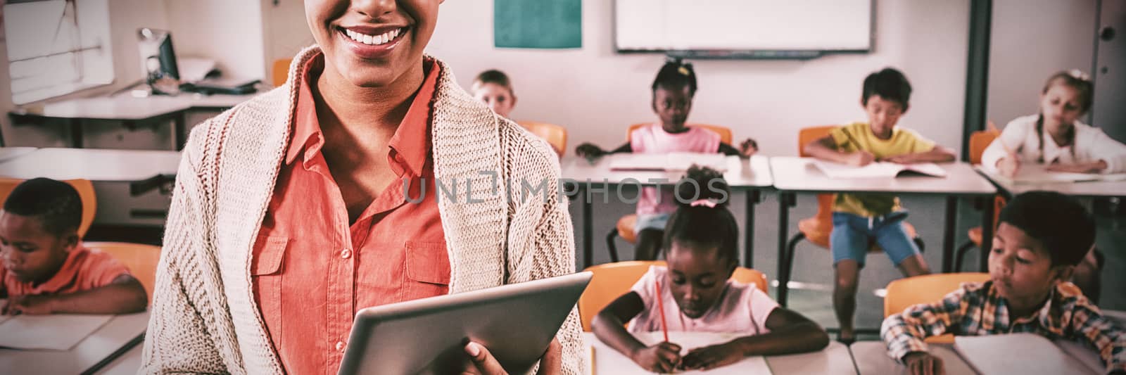 Teacher posing in front of class with tablet pc by Wavebreakmedia