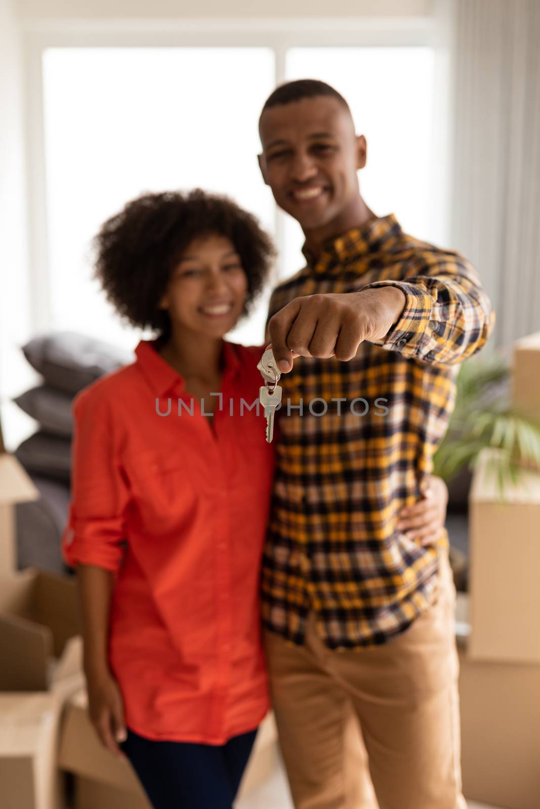 Happy couple holding new house keys in living room at home by Wavebreakmedia