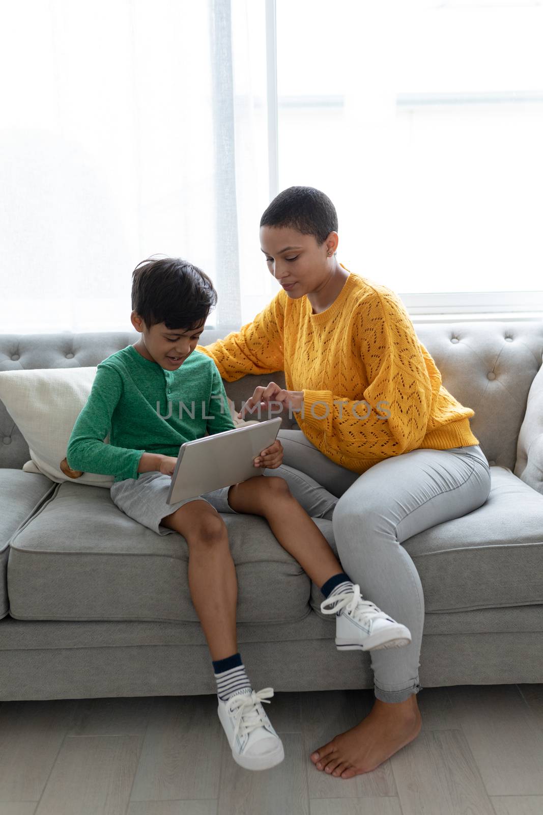 Front view of African american mother and son using digital tablet on a sofa in living room at home