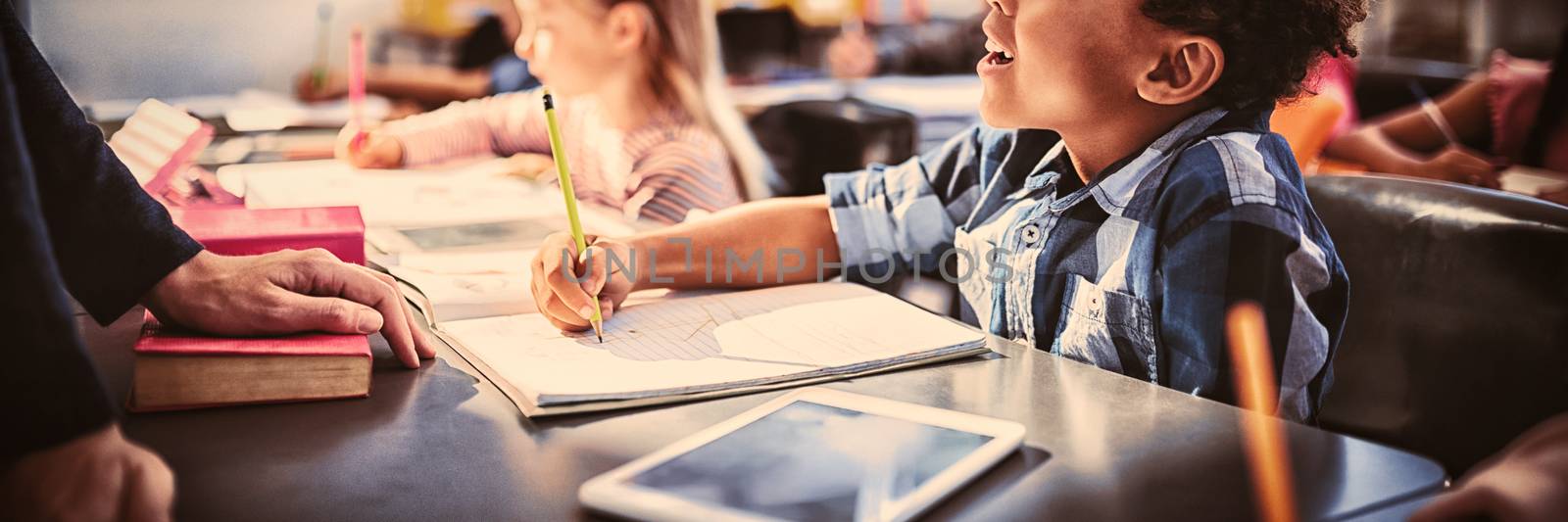 Teacher interacting with schoolboy in classroom by Wavebreakmedia