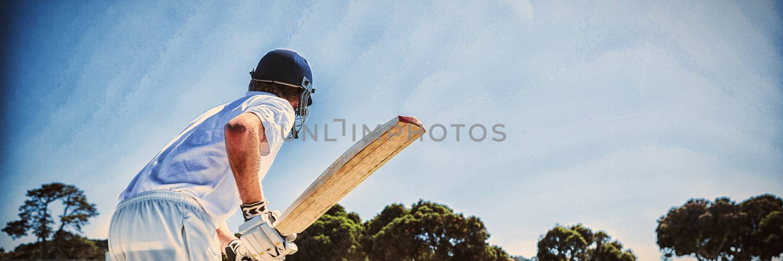 Side view of cricket player batting while playing on field against clear sky