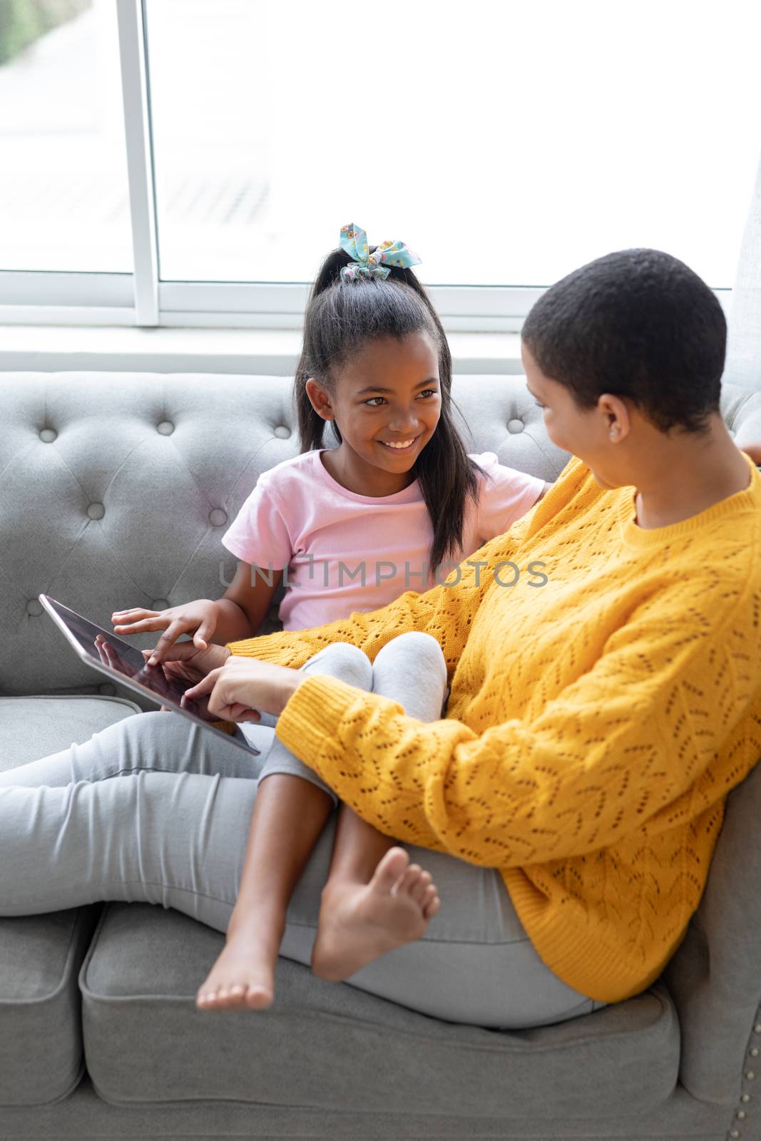 Side view of African american mother and daughter using digital tablet in living room at home