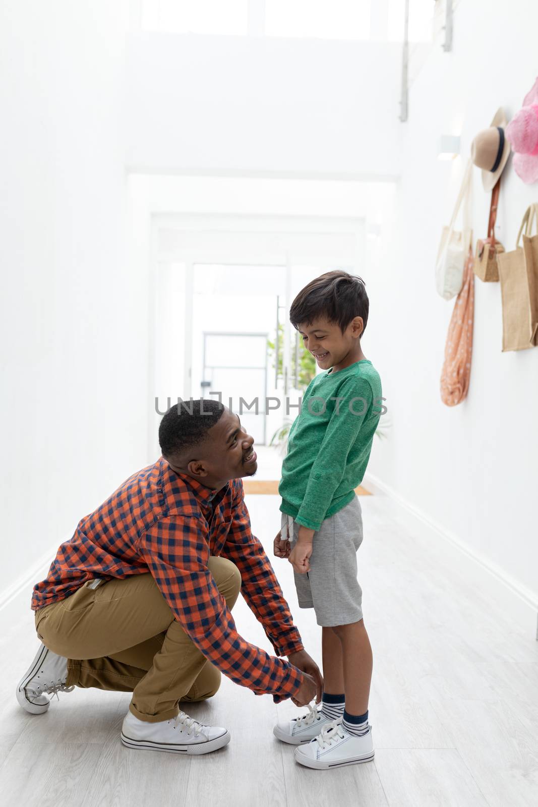 Side view of African american father tying his sons in tying shoelaces at home