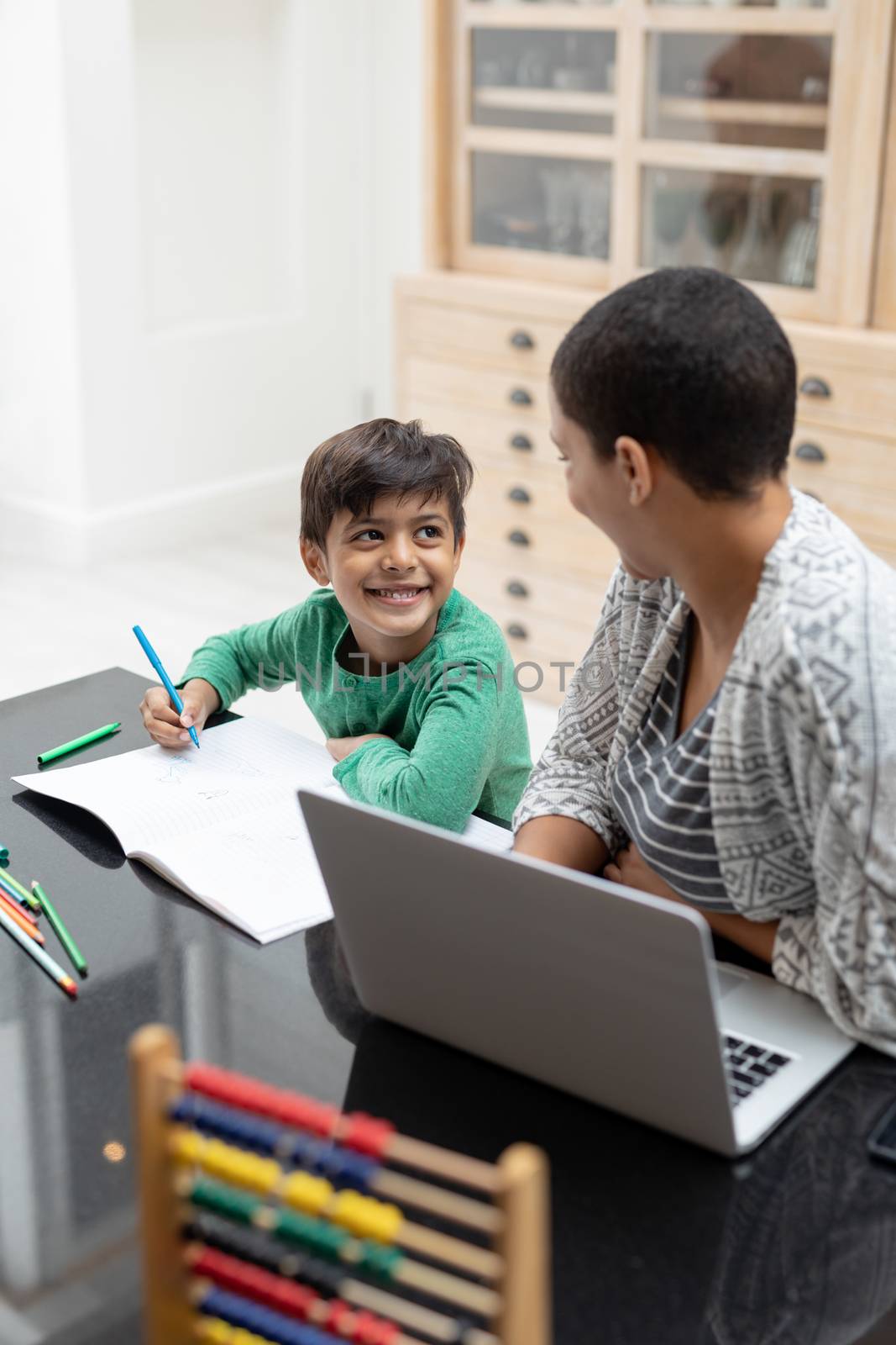 Mother helping his son with his homework on a table by Wavebreakmedia